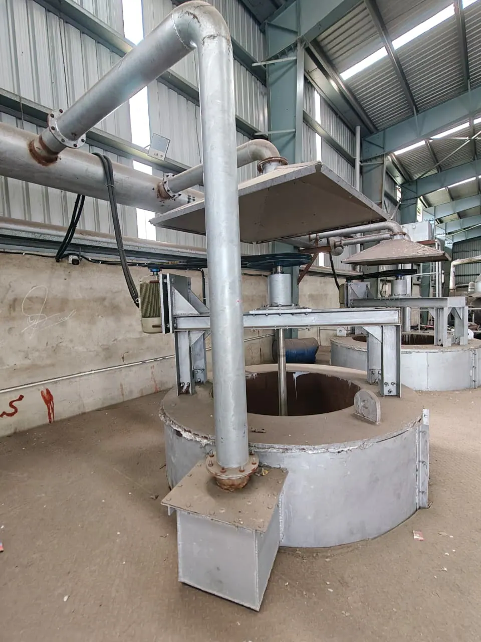 Two agitated cylindrical vessels arranged in sequence beneath extraction hoods and shared ductwork