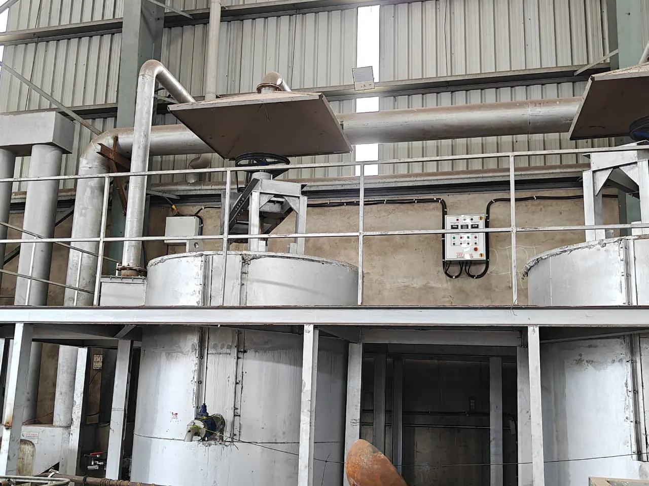 Process vessel beneath an extraction hood and belt drive with a nearby control panel and overhead duct